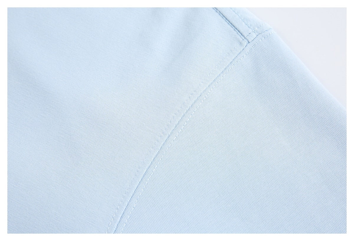 Close-up of light blue garment fabric with a curved stitched seam.