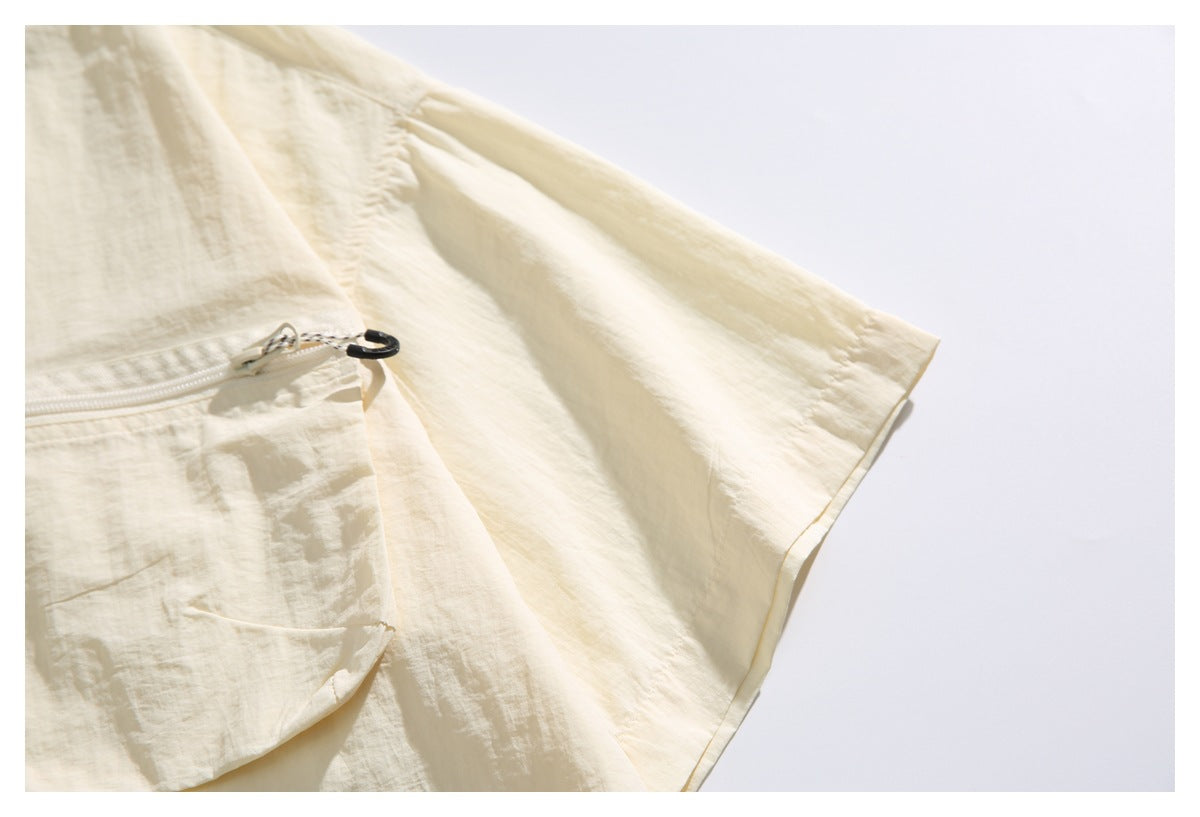 Close-up of an ivory short sleeve shirt showing a zippered chest pocket and sleeve.