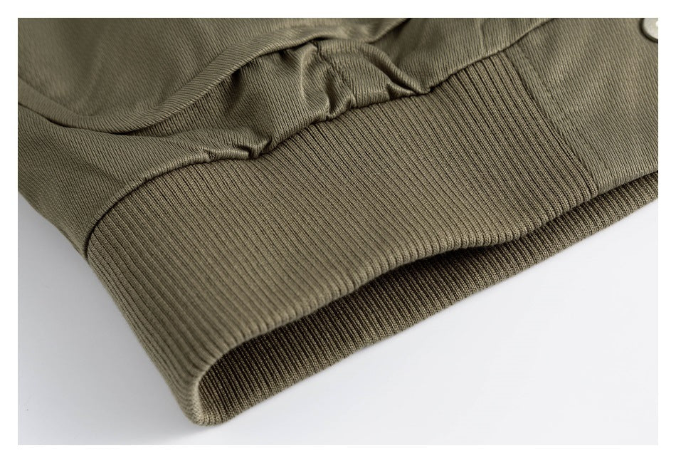 Close-up of an olive garment's wide ribbed hem and gathered fabric.