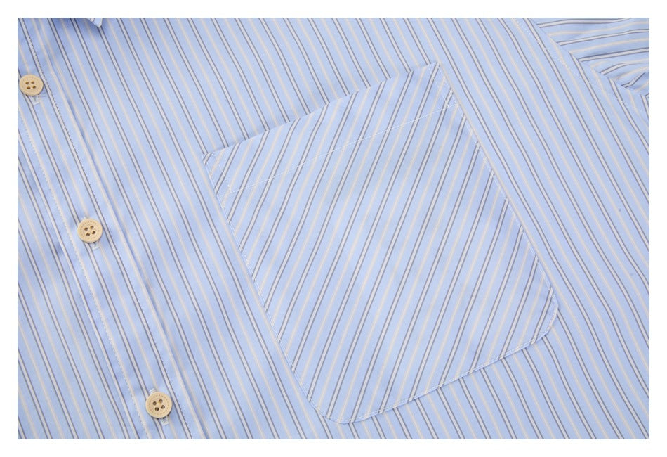 Close-up of a light blue striped shirt's chest pocket and front placket with beige buttons.