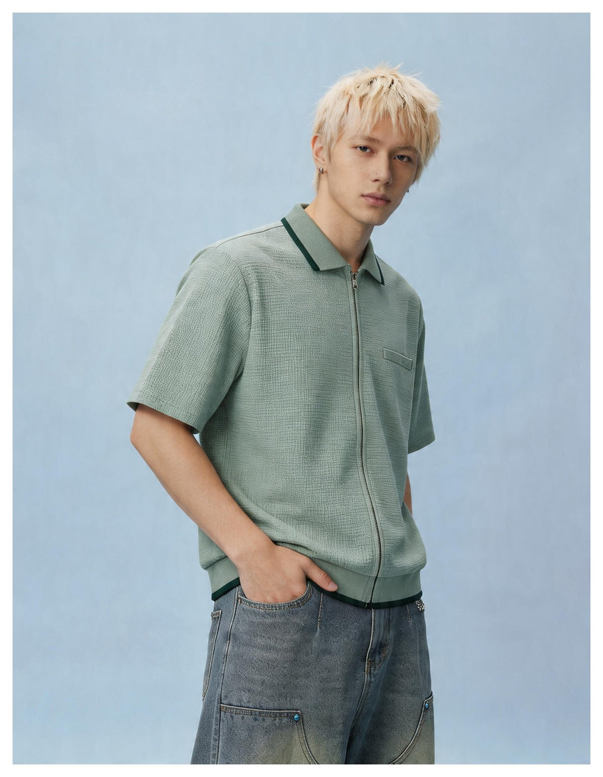 Model in the light green zip-front short-sleeve shirt, angled pose with a hand in the pocket of gray jeans