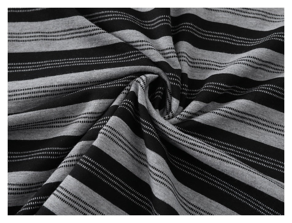 Close-up of black and gray striped fabric gathered into a swirl, showing its repeating dotted bands.