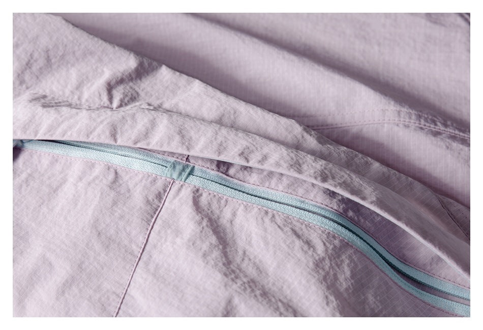 Close-up of a pale lavender jacket pocket with a light blue zipper.