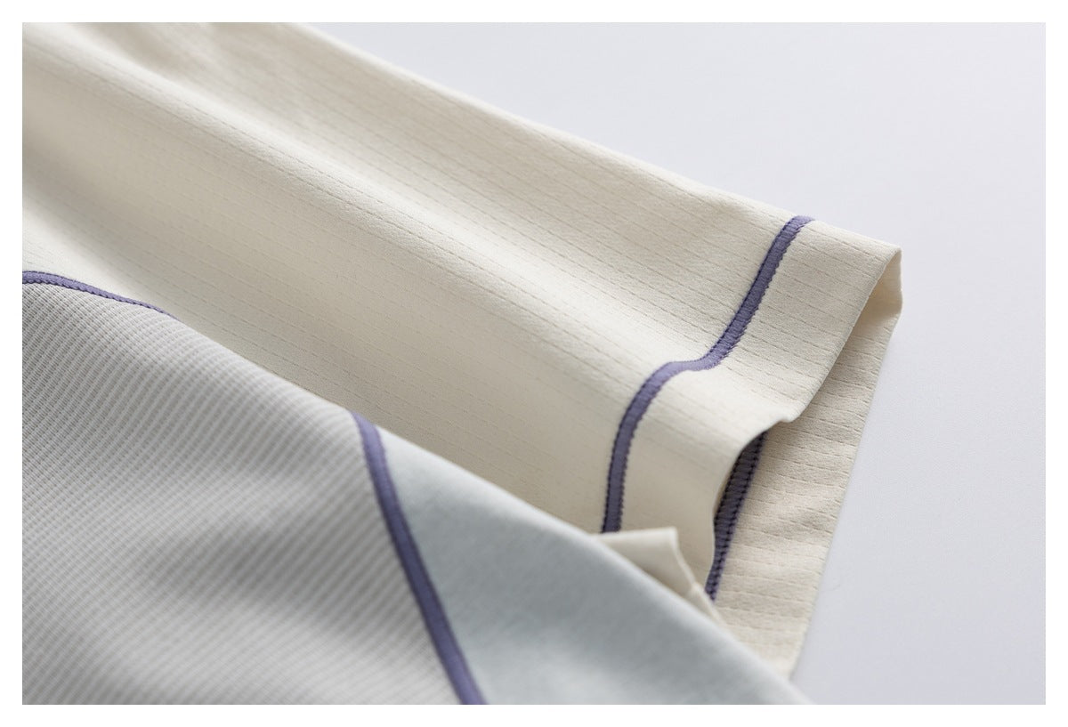 Close-up of the ivory sleeve hem and lavender seam trim against the garment's ribbed body.