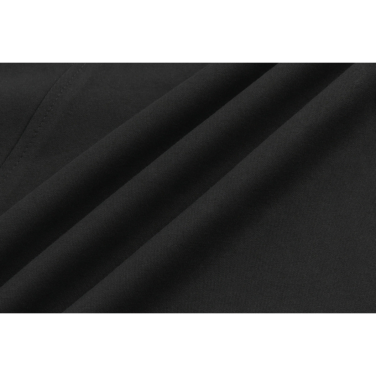 Close-up of black T-shirt fabric draped into folds, showing its surface texture and seam.