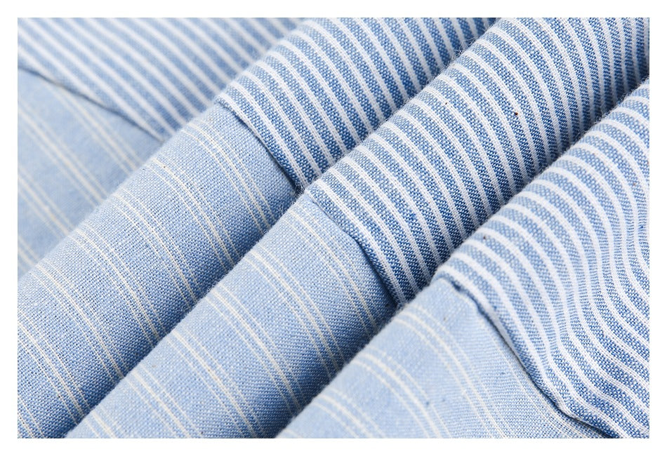 Folded blue shirt fabric showing alternating blue-and-white stripe patterns and stitching.