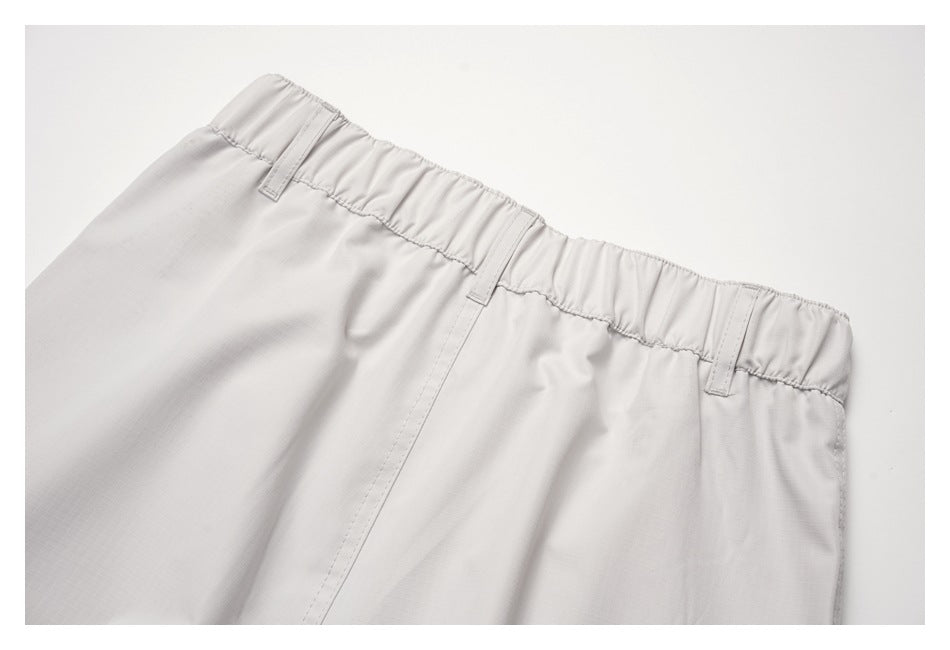 Close-up of light gray pants showing an elastic waistband and belt loops.