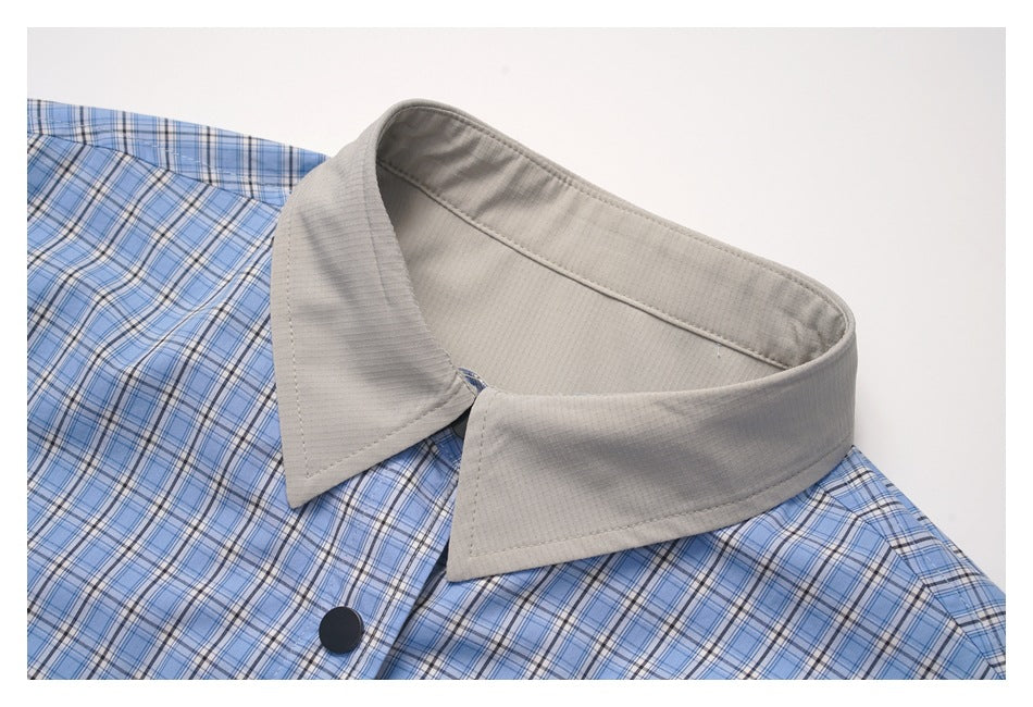 Close-up of the shirt's beige pointed collar, blue plaid fabric, and a dark front button.