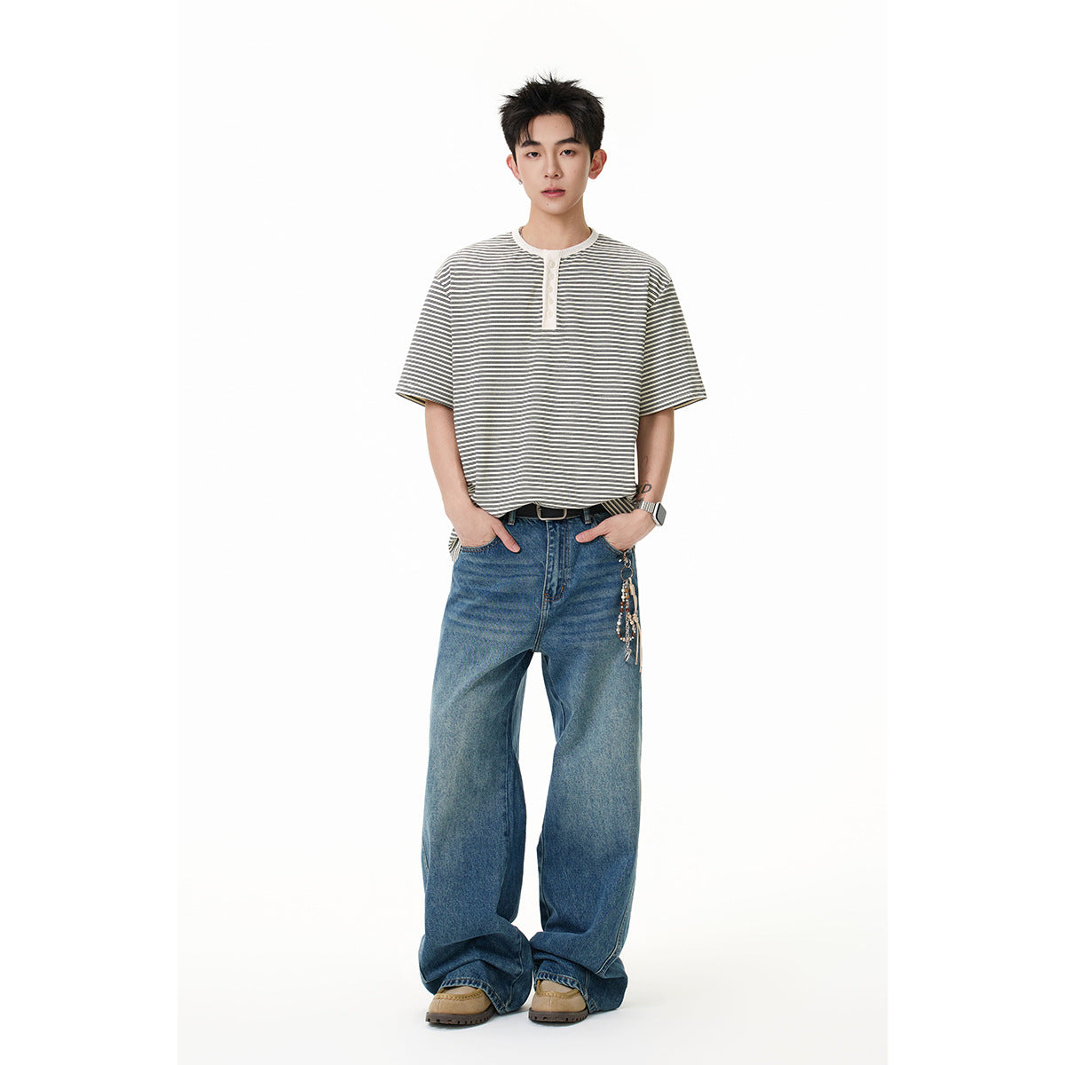 Full-length model wearing an off-white and dark striped short-sleeve henley with wide-leg blue jeans.