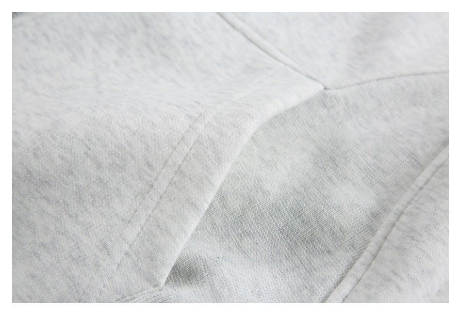 Close-up of curved stitched panel seams on a light gray heather garment.