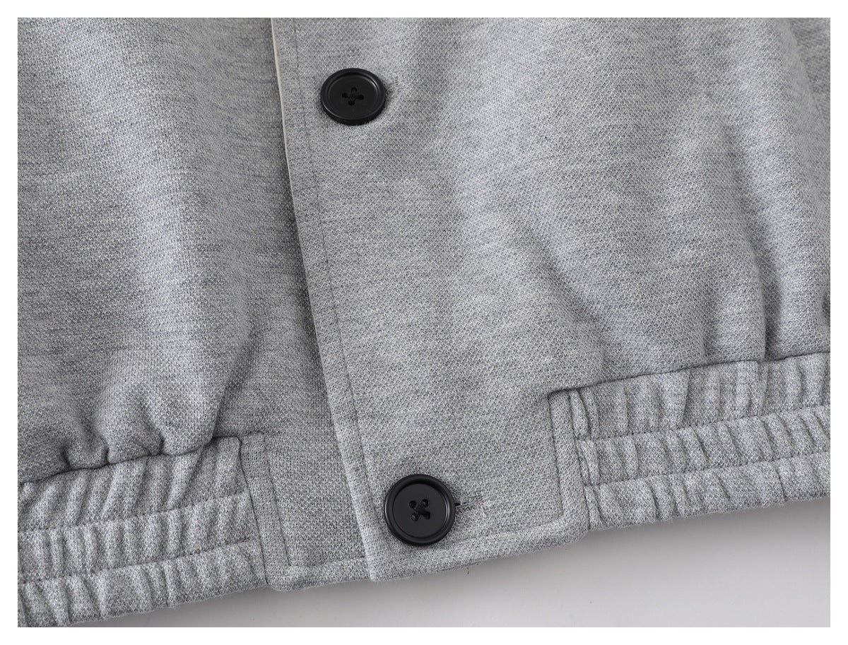 Close-up of the light gray jacket hem with black buttons and a gathered elastic section.