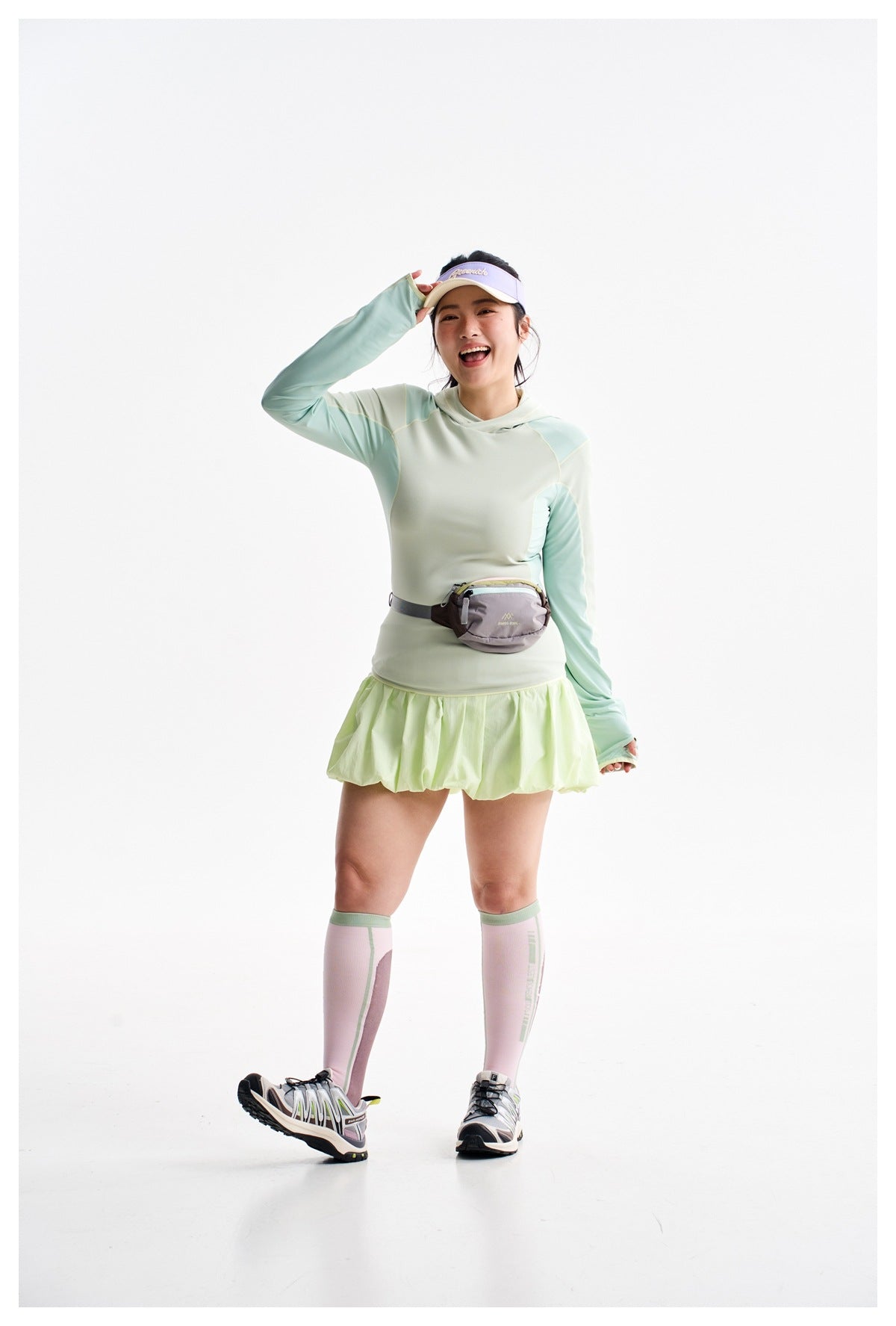 Front view of a model in a pale mint color-block hooded top and lime bubble-hem tennis skirt.