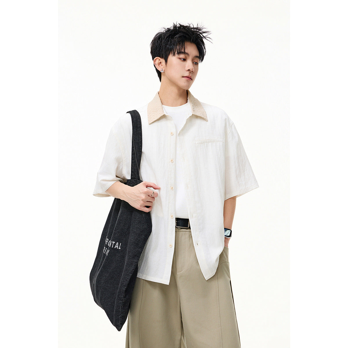 Model wearing a white short-sleeve button-up shirt with a beige textured collar and chest pocket, paired with tan trousers.