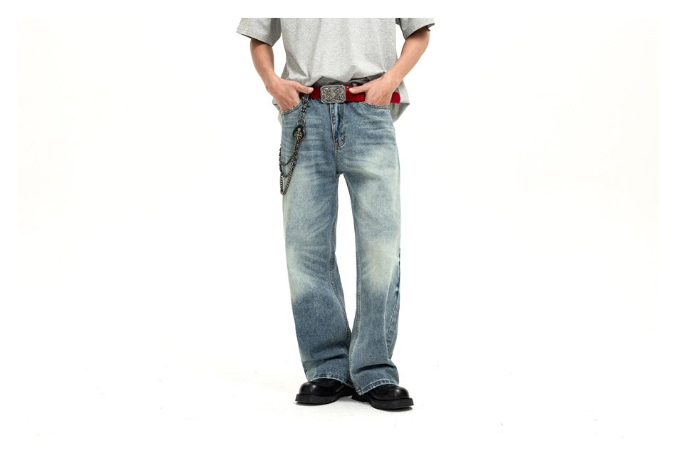 Cropped model wearing loose light-wash blue jeans, a gray T-shirt, red belt and chain against a white background.