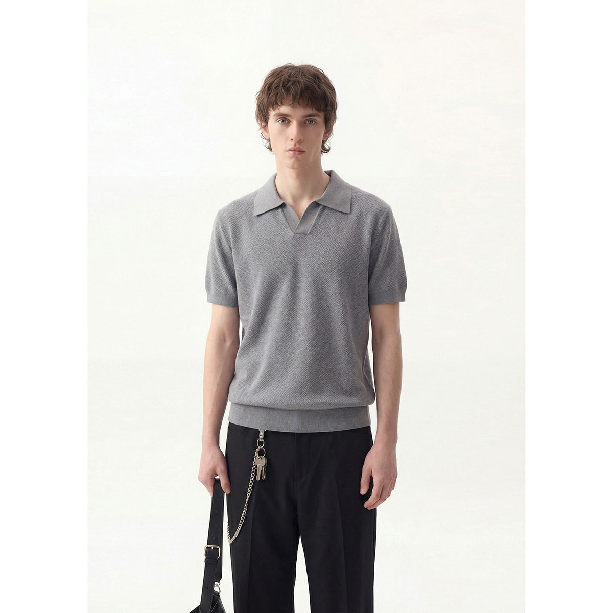 Front view of a model wearing a textured gray short-sleeve polo-style pullover with a pointed collar and ribbed hem.