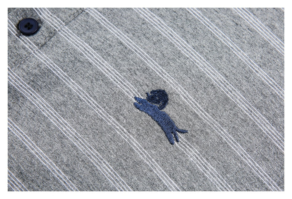 Close-up of a navy embroidered animal motif on gray fabric with thin white stripes.