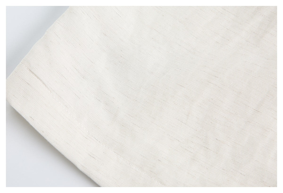 Close-up of the cream garment's subtly textured fabric and seam.