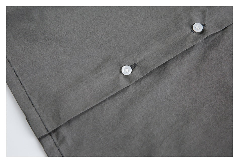 Close-up of a charcoal gray garment placket with two small white buttons and visible stitching.