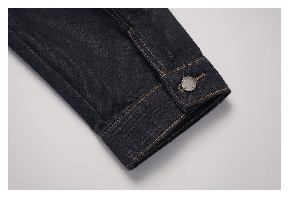 Close-up of a dark denim jacket cuff with a buttoned tab and contrast stitching.