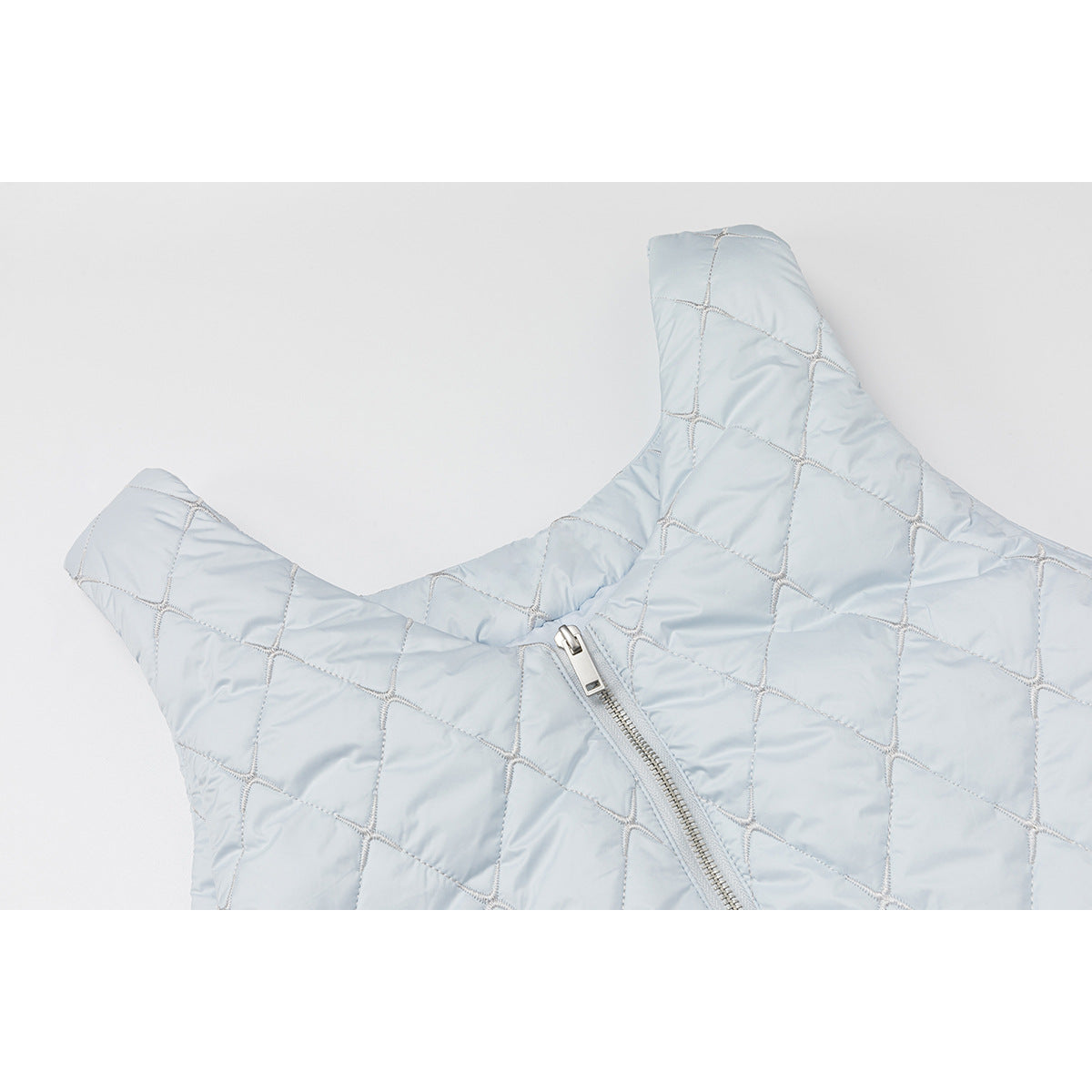 Close-up of a pale blue quilted vest with diamond stitching and a silver zipper.