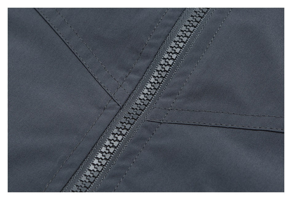 Close-up of a dark charcoal garment’s front zipper and surrounding stitched panels.