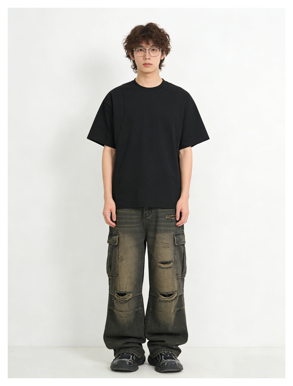 Model wearing a black relaxed T-shirt with distressed washed cargo jeans, front view