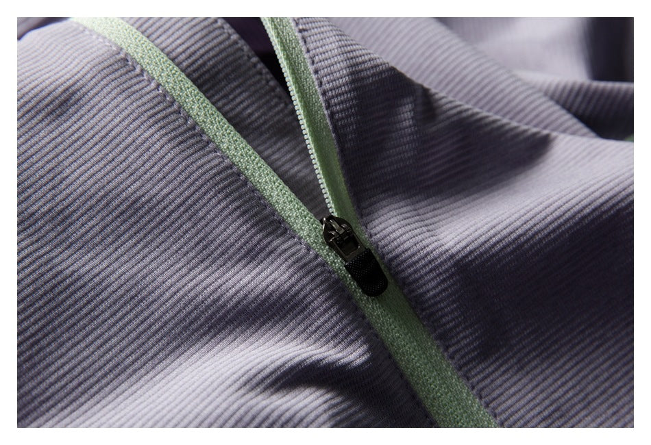 Close-up of a black zipper with pale green tape on pale lavender-gray ribbed fabric.