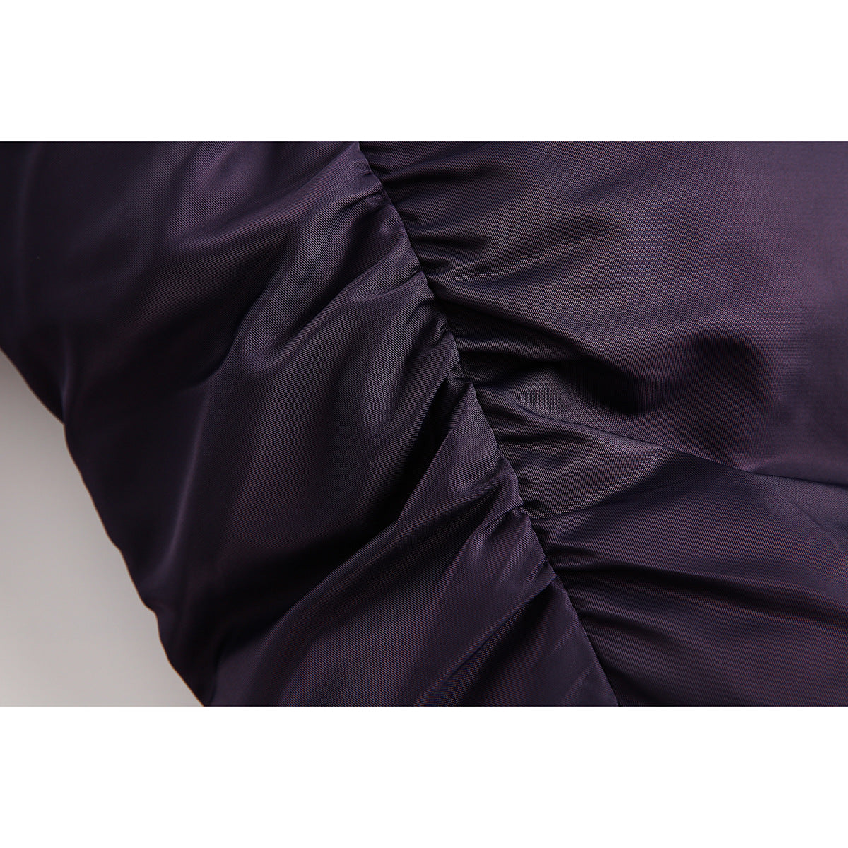 Close-up of gathered, glossy dark purple jacket fabric.