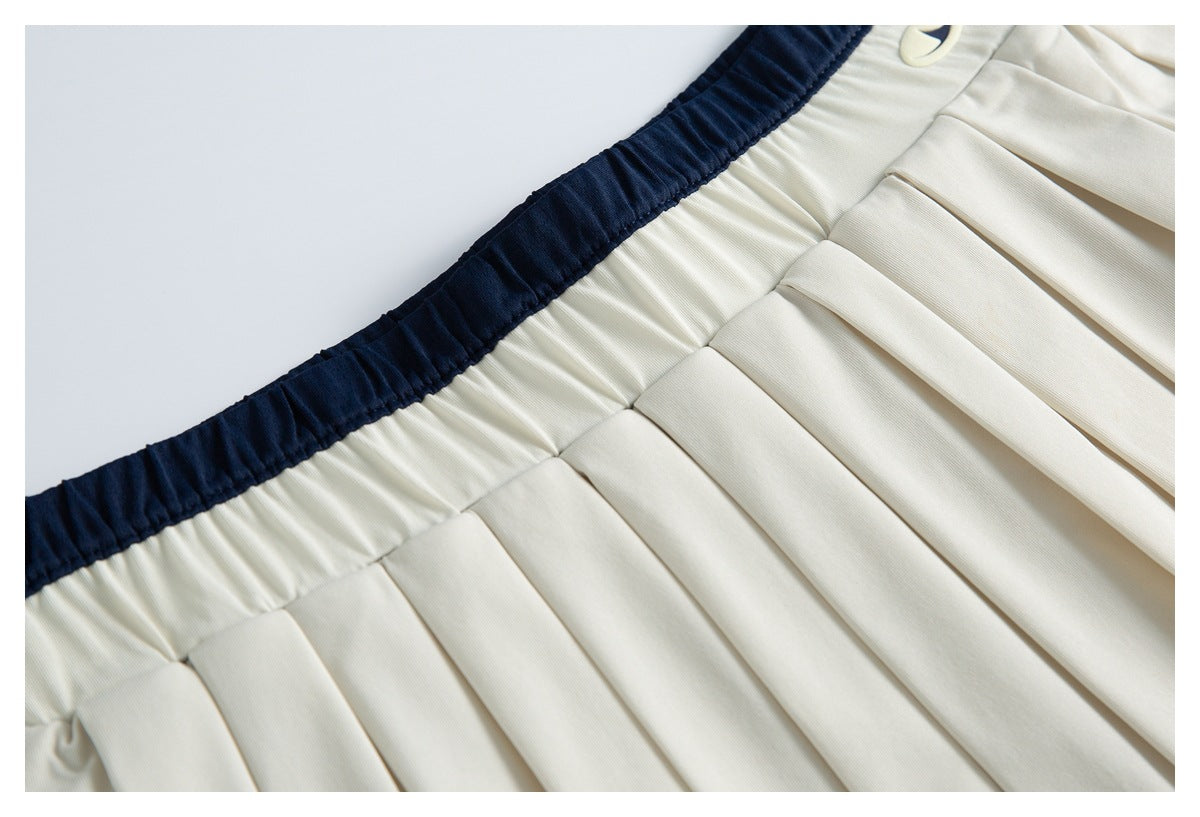 Close-up of cream pleats meeting a dark navy elastic waistband.