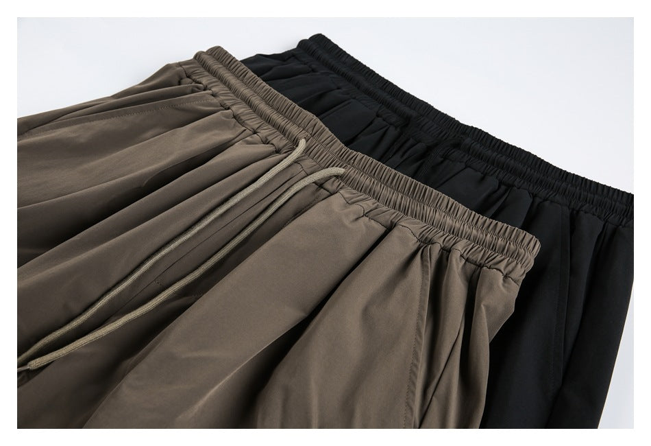Close-up of taupe and black shorts showing gathered elastic waistbands and a taupe drawstring.