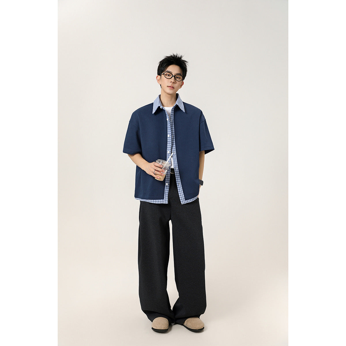 Model wearing a navy short-sleeve button-up shirt with blue plaid collar, placket and hem trim.