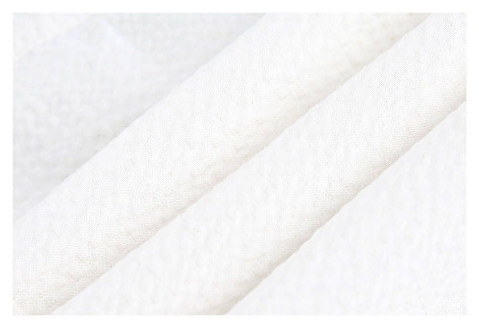 Close-up of white fabric with a subtle textured surface and diagonal folds.