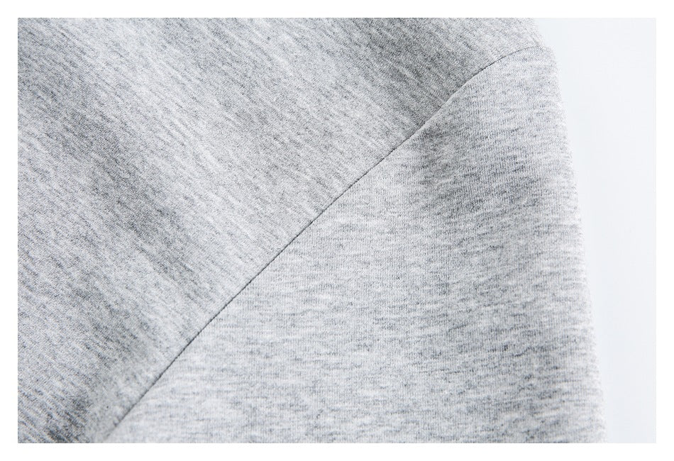 Close-up of a curved shoulder seam on a gray heather knit garment.
