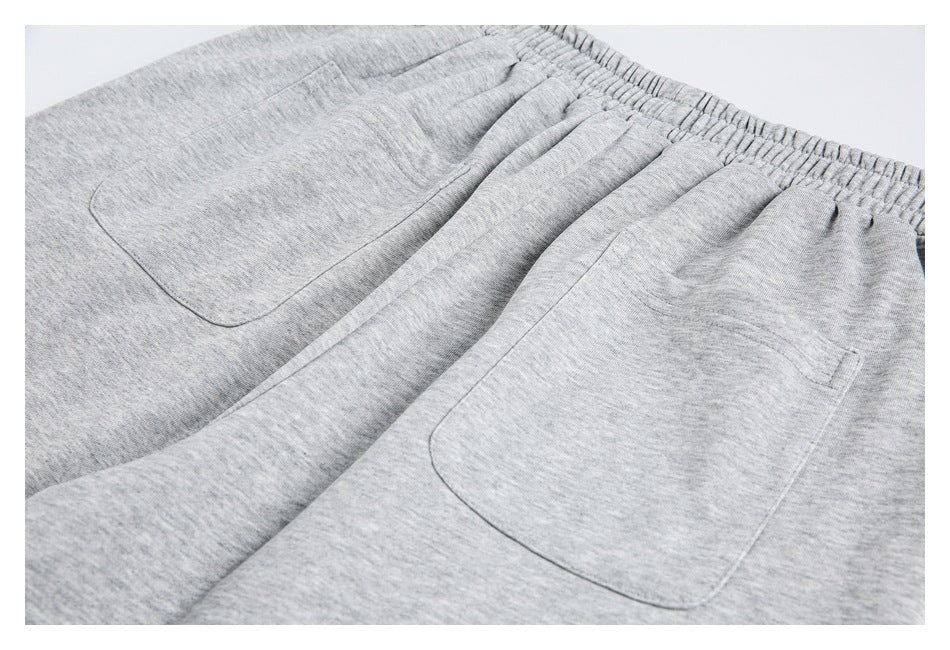 Close-up of light gray heather sweatpants with an elastic waistband and two patch pockets.