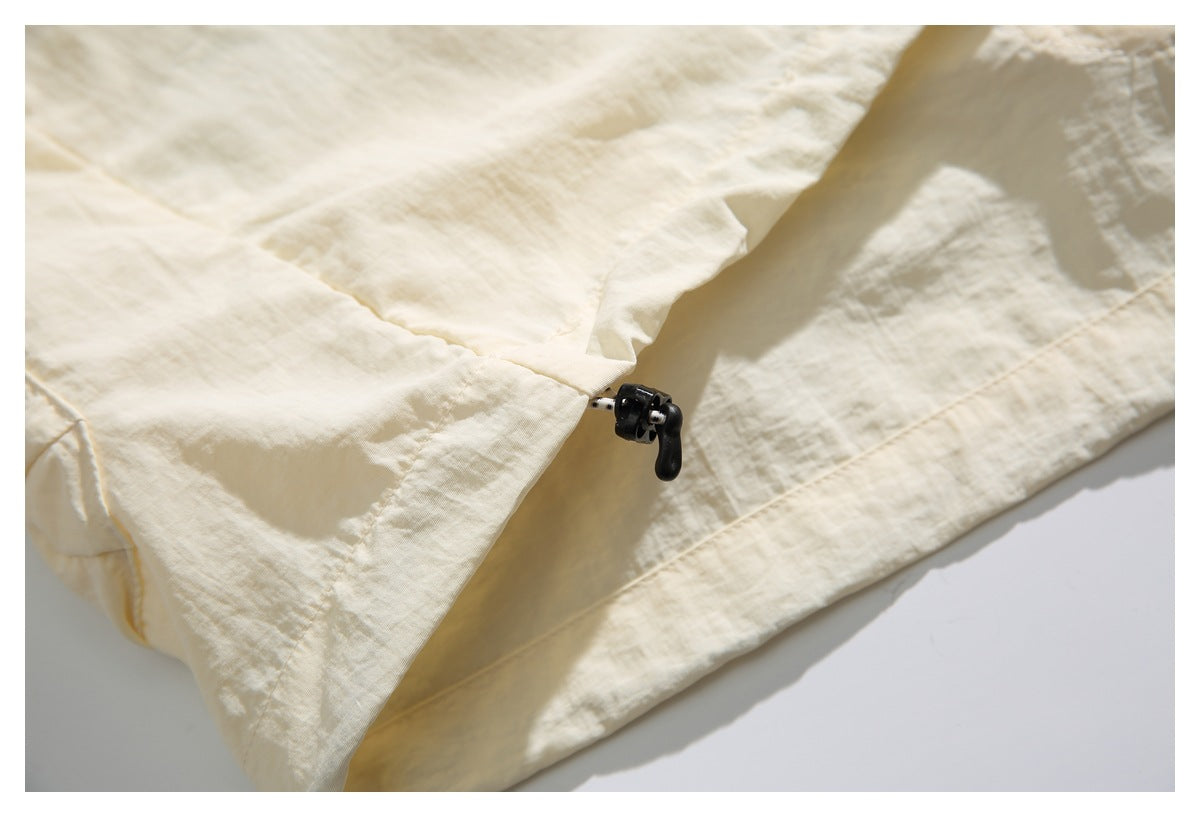 Close-up of the ivory shirt hem with an adjustable black drawcord toggle.