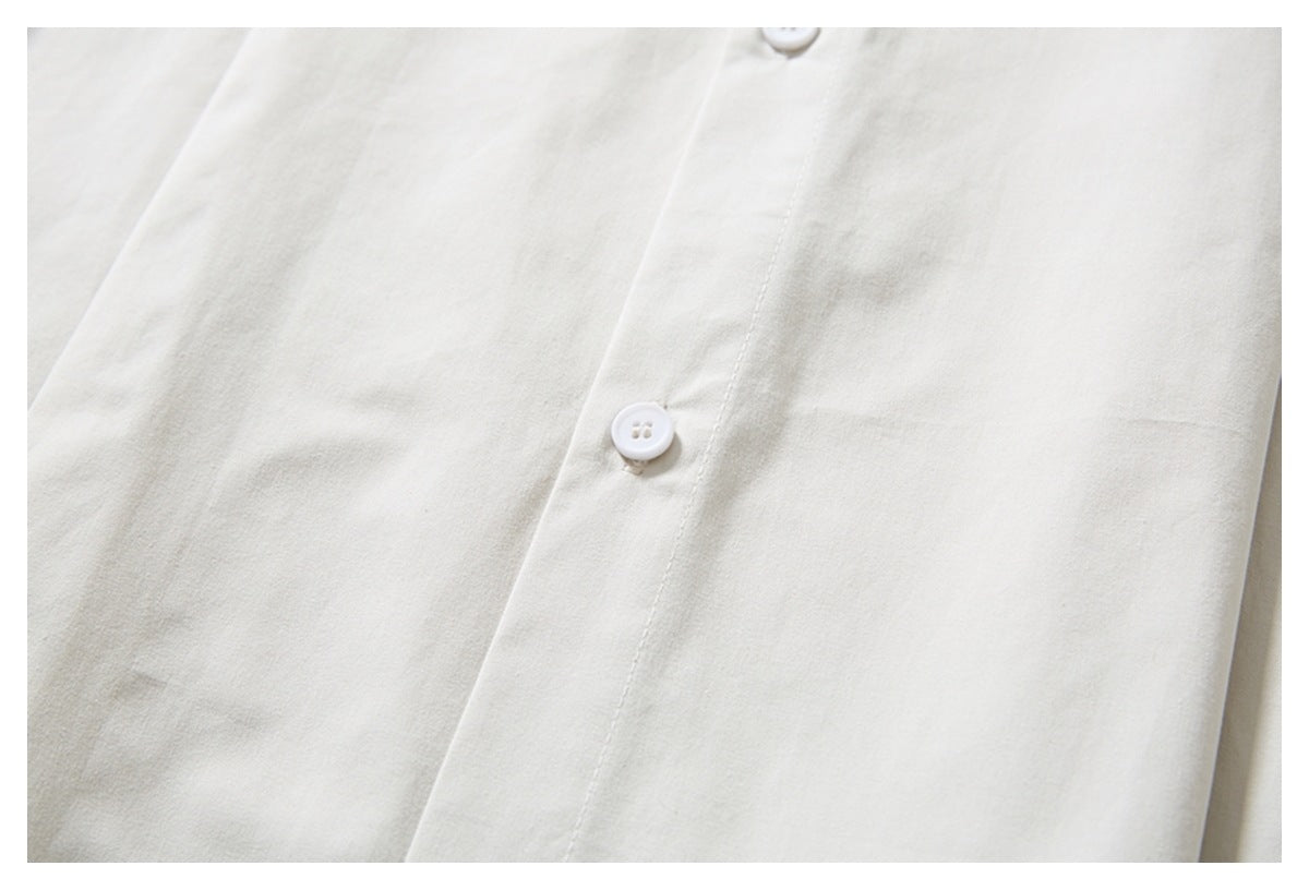 Close-up of an ivory shirt's front placket and white buttons.