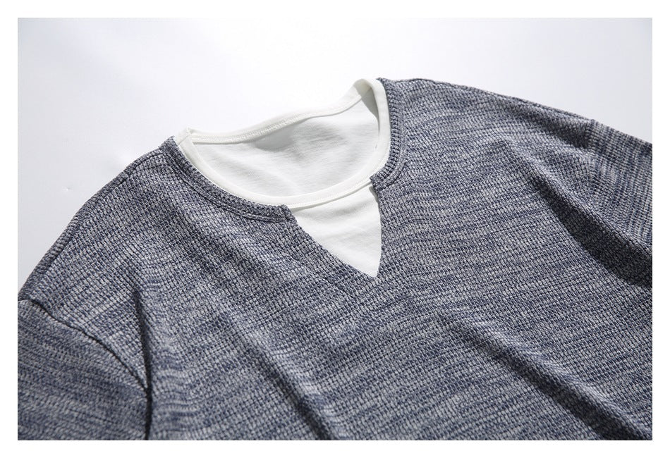 Close view of a gray-blue textured short-sleeve top with a white crew-neck layer and a notched neckline, laid flat.
