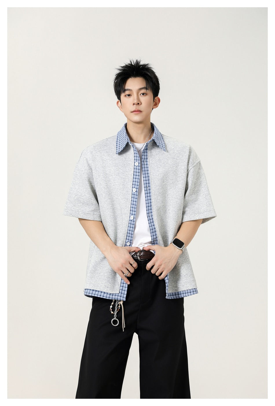 Model wearing a light gray short-sleeve button-up shirt with blue plaid collar, placket and hem trim.