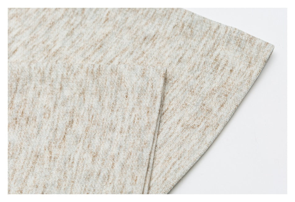 Close-up of a seam and overlapping panel on beige marled fabric.
