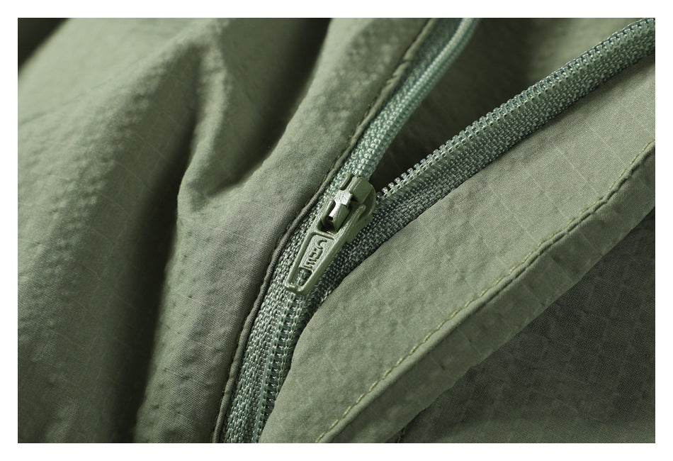 Close-up of a gray-green zipper and stitching on matching fabric.