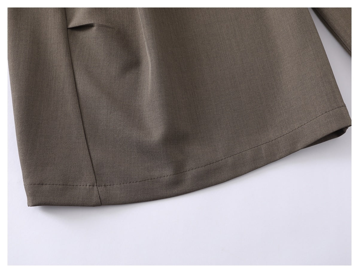 Close-up of the taupe trousers' stitched hem and side seam.