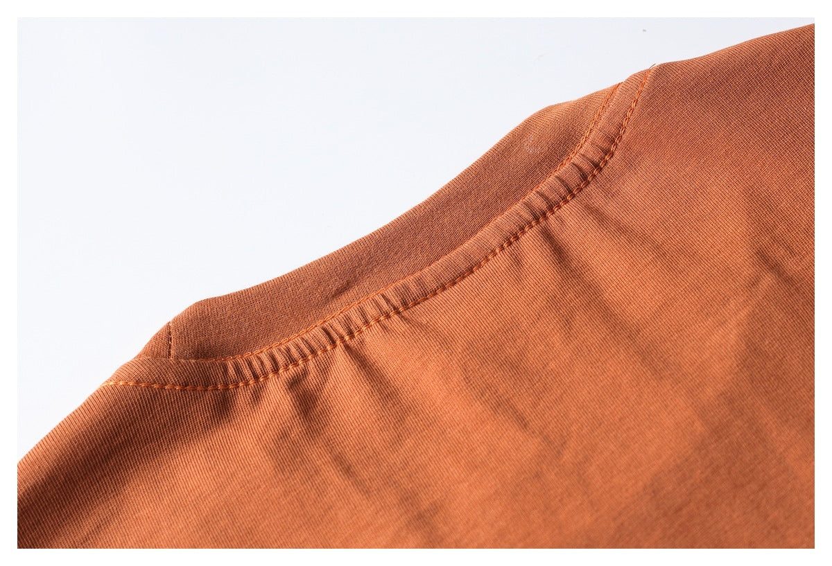 Close-up of a rust-orange garment neckline with ribbed trim and visible stitching.
