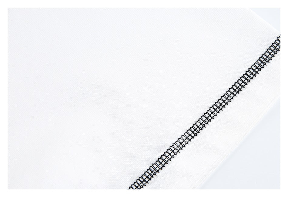 Close-up of black overlock stitching running diagonally across white garment fabric.