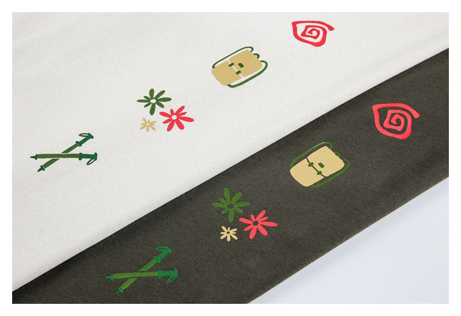 White and dark olive fabric panels show matching colorful prints of flowers, crossed tools, a pouch and a spiral.