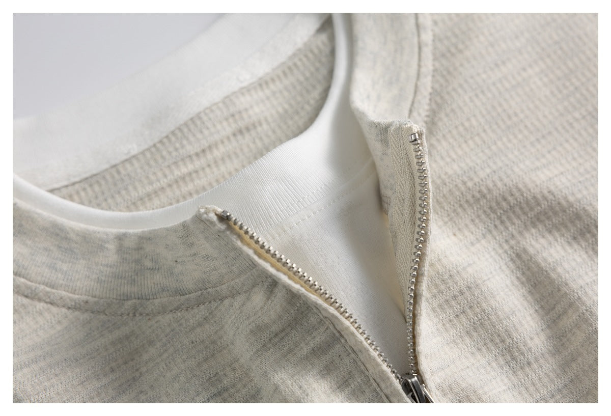 Close-up of the top's partially open silver zipper, white inner neckline, and light gray knit fabric.
