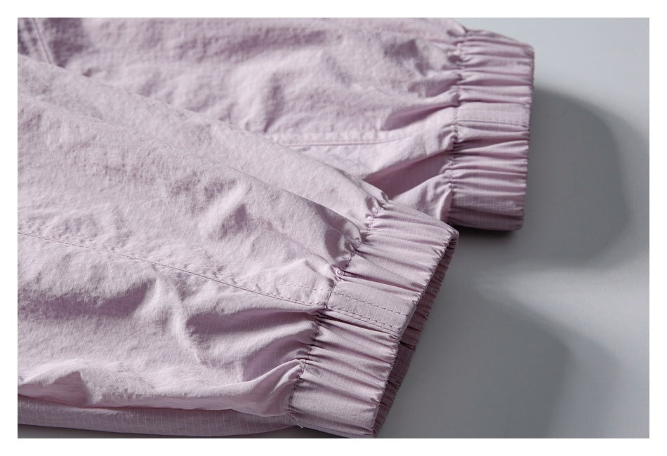 Close-up of two pale pink garment sleeves with gathered elastic cuffs and fine grid lines.