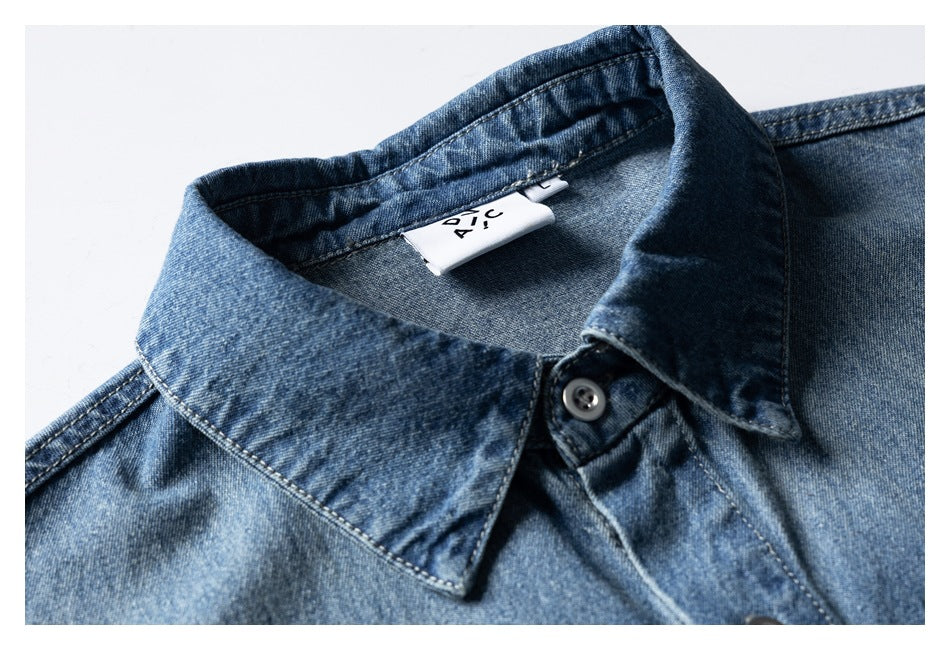 Close-up of a blue denim shirt collar, button, and interior label.