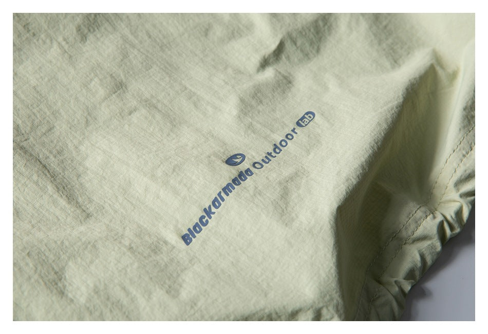 Close-up of blue Blackmamba Outdoor Lab print on pale sage fabric, with a stitched edge at right.