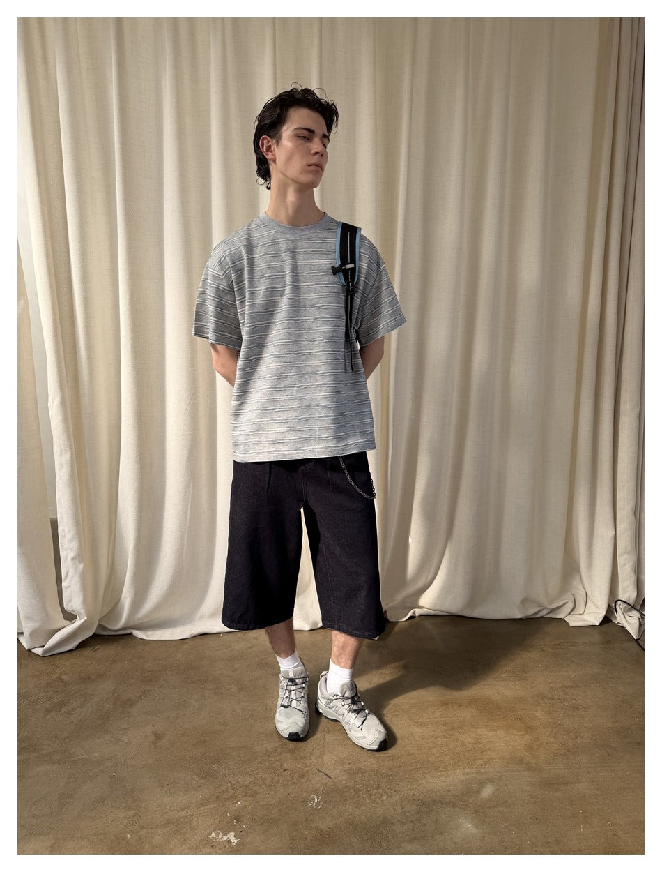 Model wearing an oversized gray T-shirt with irregular white and blue horizontal stripes.