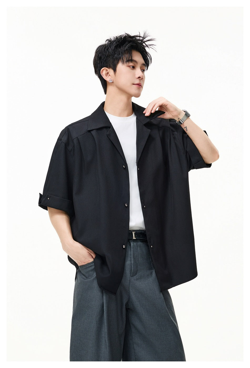 Model wearing a black oversized short-sleeve button-up shirt, shown from the waist up.